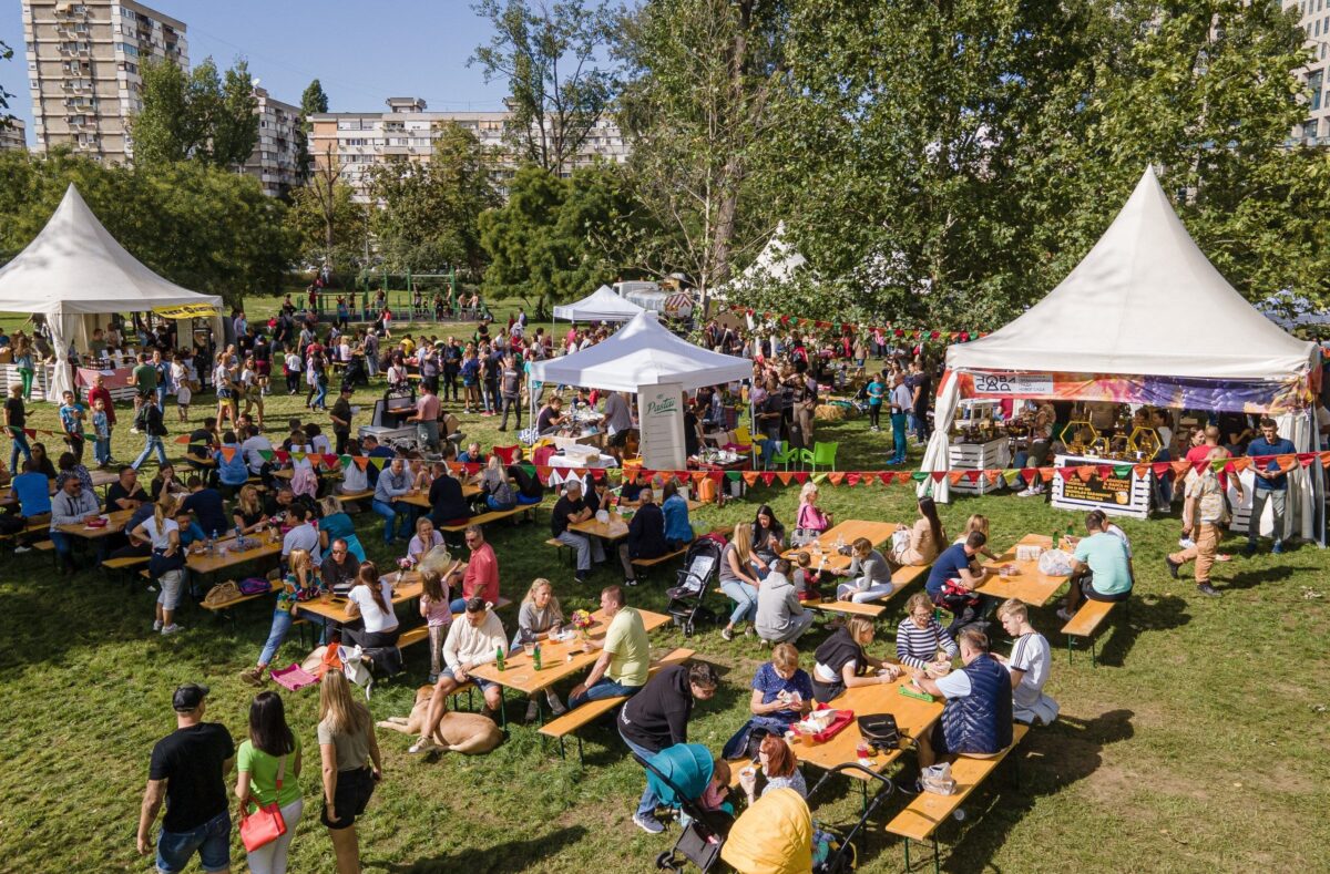 Park Limani u Novom Sadu ispunjen ljudima koji sede za stolovima ispred i u satorima tokom festivala Ukusi Vojvodine