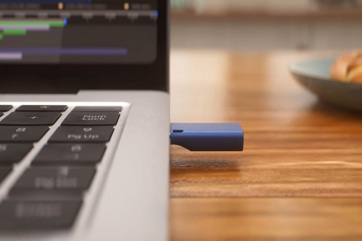 Plavi USB fleš priključen u bočnu stranu srebrnog laptopa