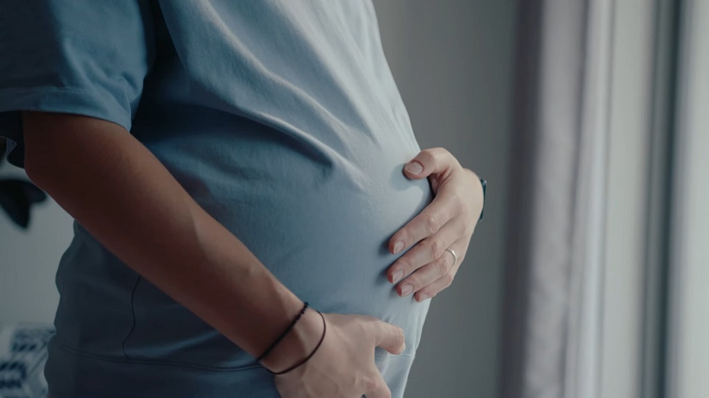 Trudnica stoji i drลพi stomak u mirnom okruลพenju