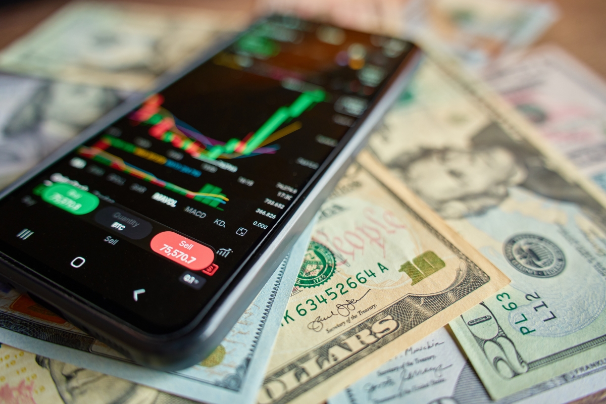 prikaz akcija na telefonu i dolara na stolu