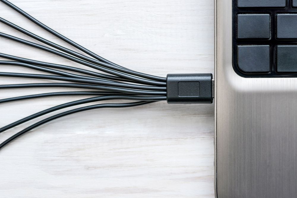 Uredno grupisani kablovi pored laptopa na radnom stolu uz organizator za kablove.